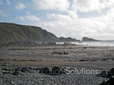 Shingle beach with distictive rock 'lines' and waterfall